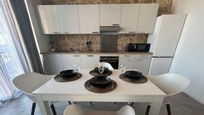 Une cuisine moderne avec des meubles blancs, un four encastré et un four à micro-ondes.