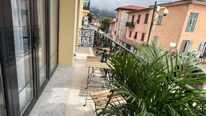 Un balcon avec un pot de fleurs, une table et des chaises.