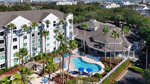 A hotel with a swimming pool, multiple floors, and palm trees. - Univeral Disney Epic Shuttle (Orlando)