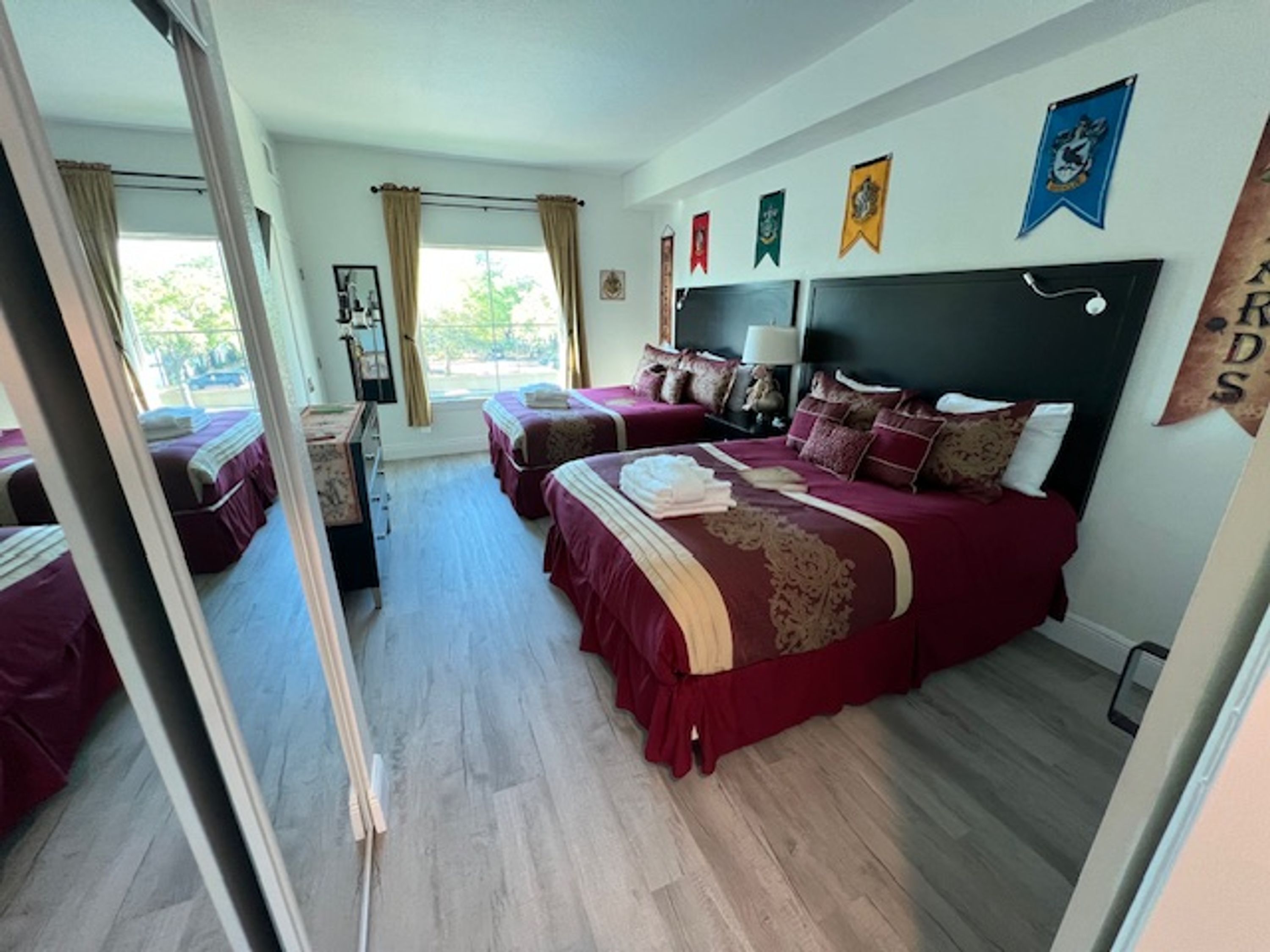 Ein Hotelzimmer mit zwei Betten, einem großen Fenster mit Vorhängen und mehreren Wanddekorationen.