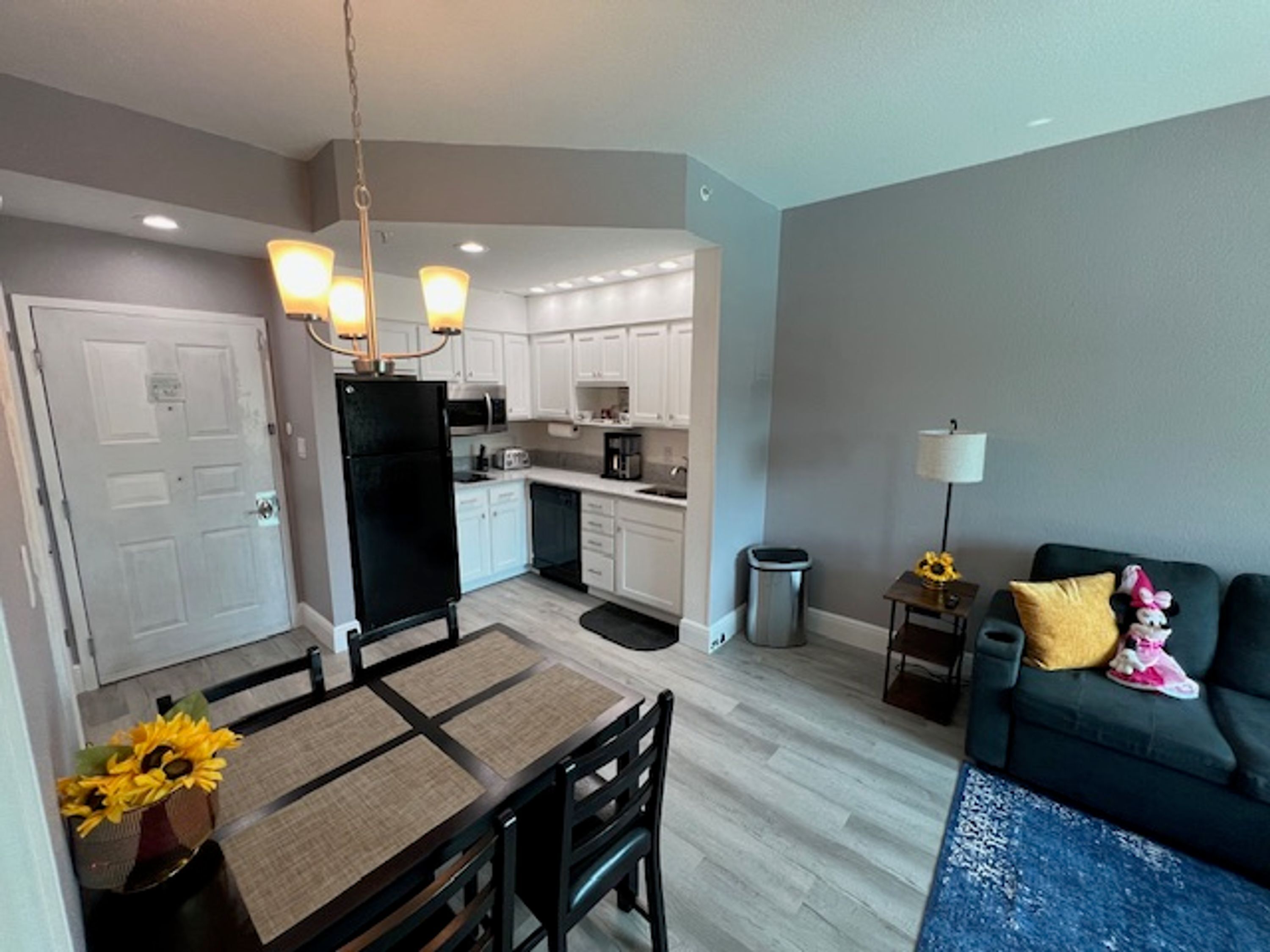 A modern kitchen with white cabinets, a black refrigerator, and a dining area with a table and chairs.