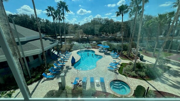A resort pool area with multiple pools, lounge chairs, and palm trees. - Univeral Disney Epic Shuttle (Orlando)