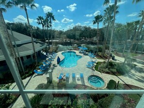 A resort pool area with multiple pools, lounge chairs, and palm trees.