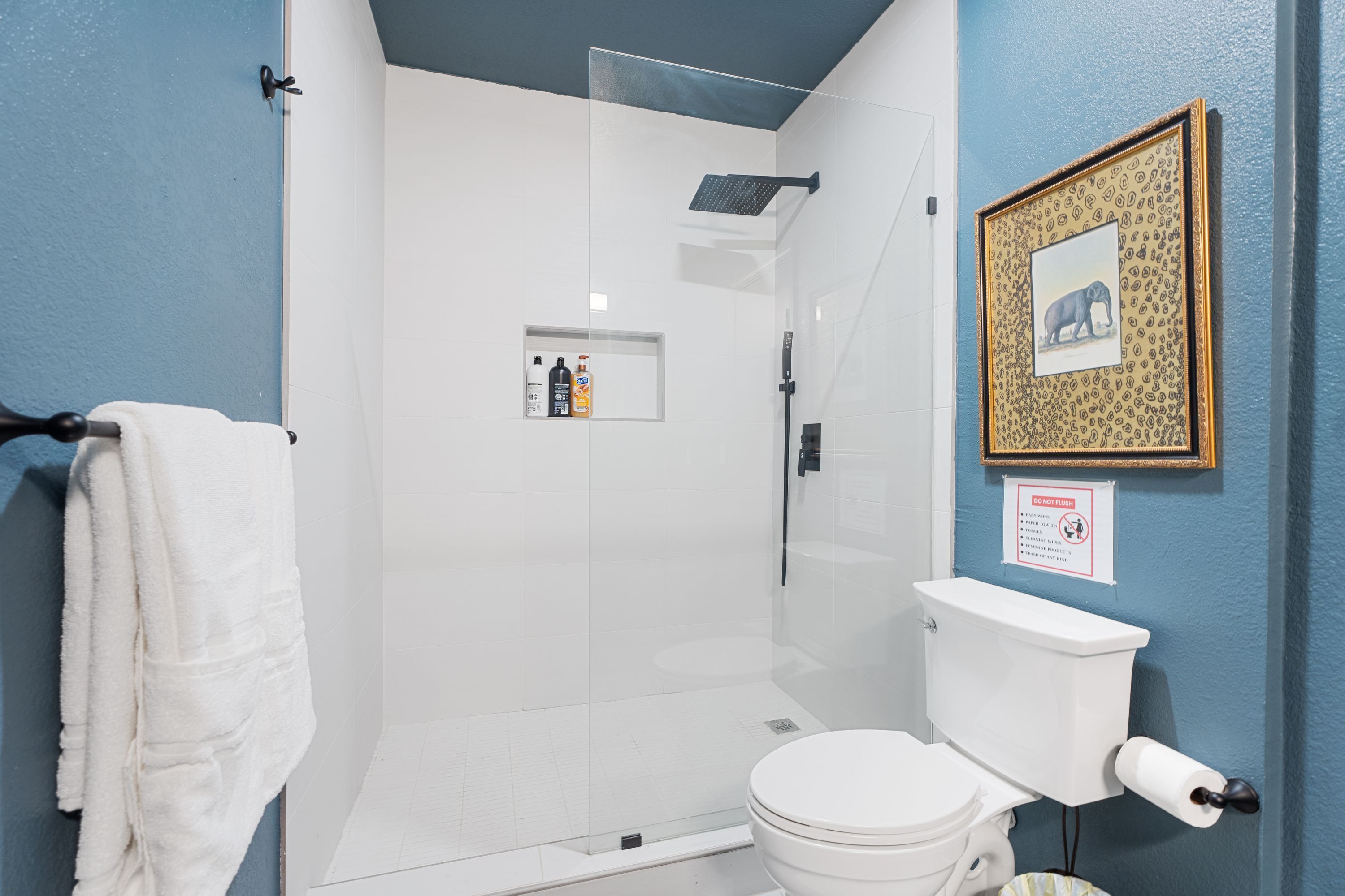 A bathroom with a glass-enclosed shower, a toilet, and a towel rack.