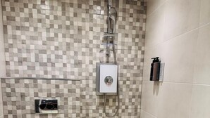 Un baño con pared de ducha azulejada, inodoro y lavamanos.