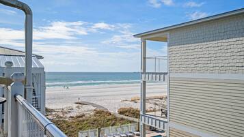 A beachfront property with a pool, beach view, and a covered patio area.