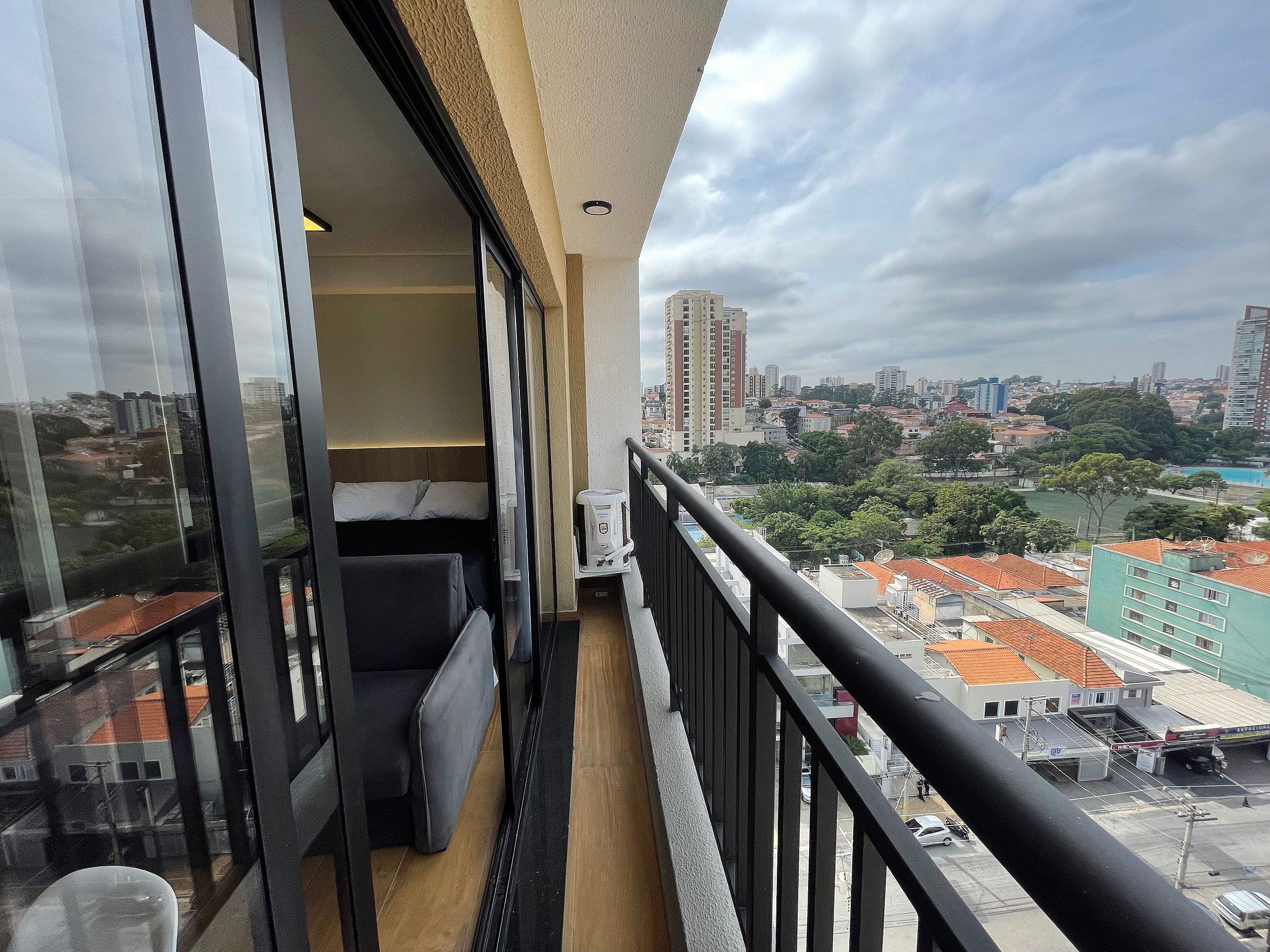 A balcony with a view of a cityscape, including buildings and a body of water.