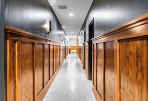 Stroll down this elegant corridor, lined with paneling and polished concrete floors, leading to a well-lit area.