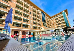 A hotel with multiple balconies, a swimming pool, and outdoor seating areas. - AMH Hotel (Durrës)