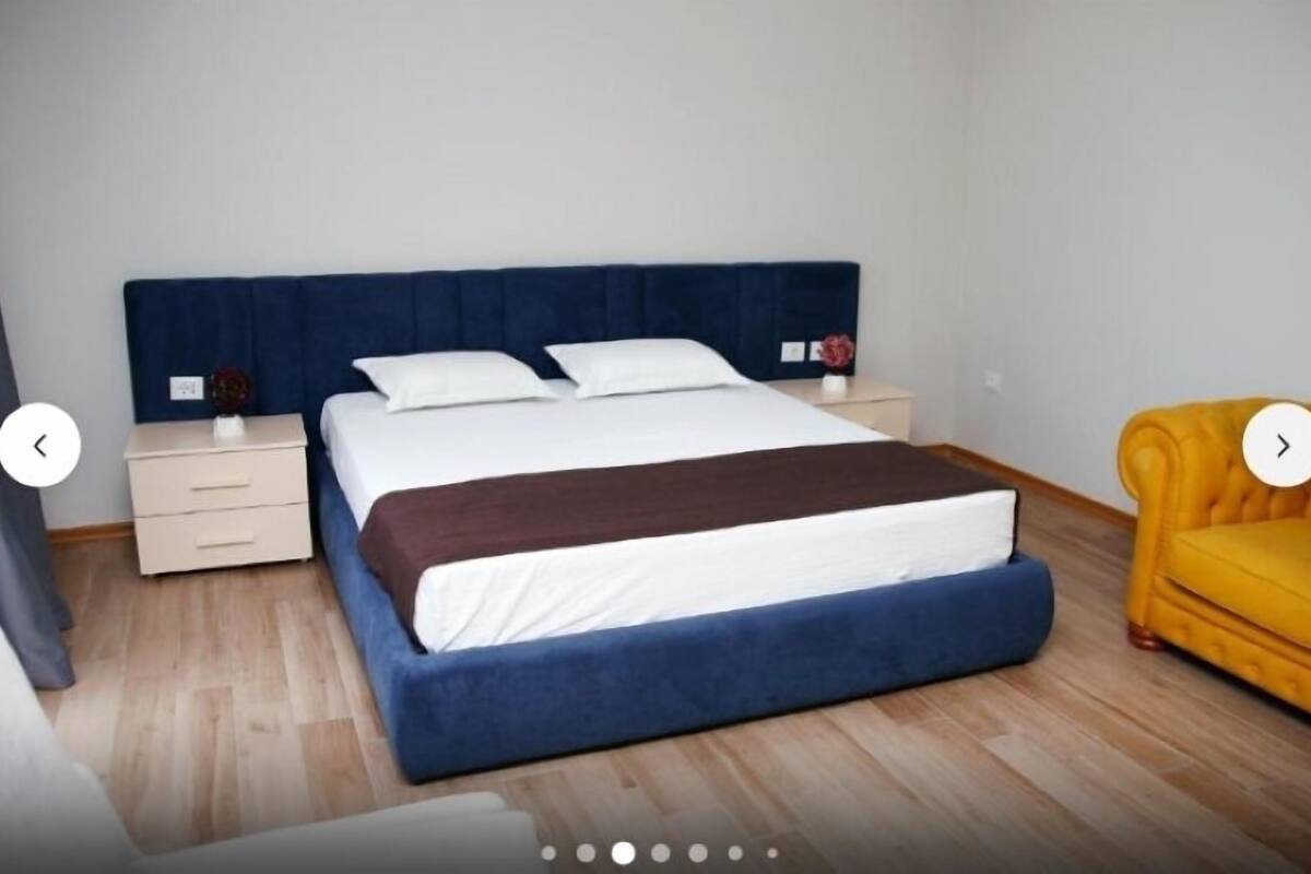 Makuuhuone, jossa on sänky, yöpöydät, yölamppu ja keltainen nojatuoli.