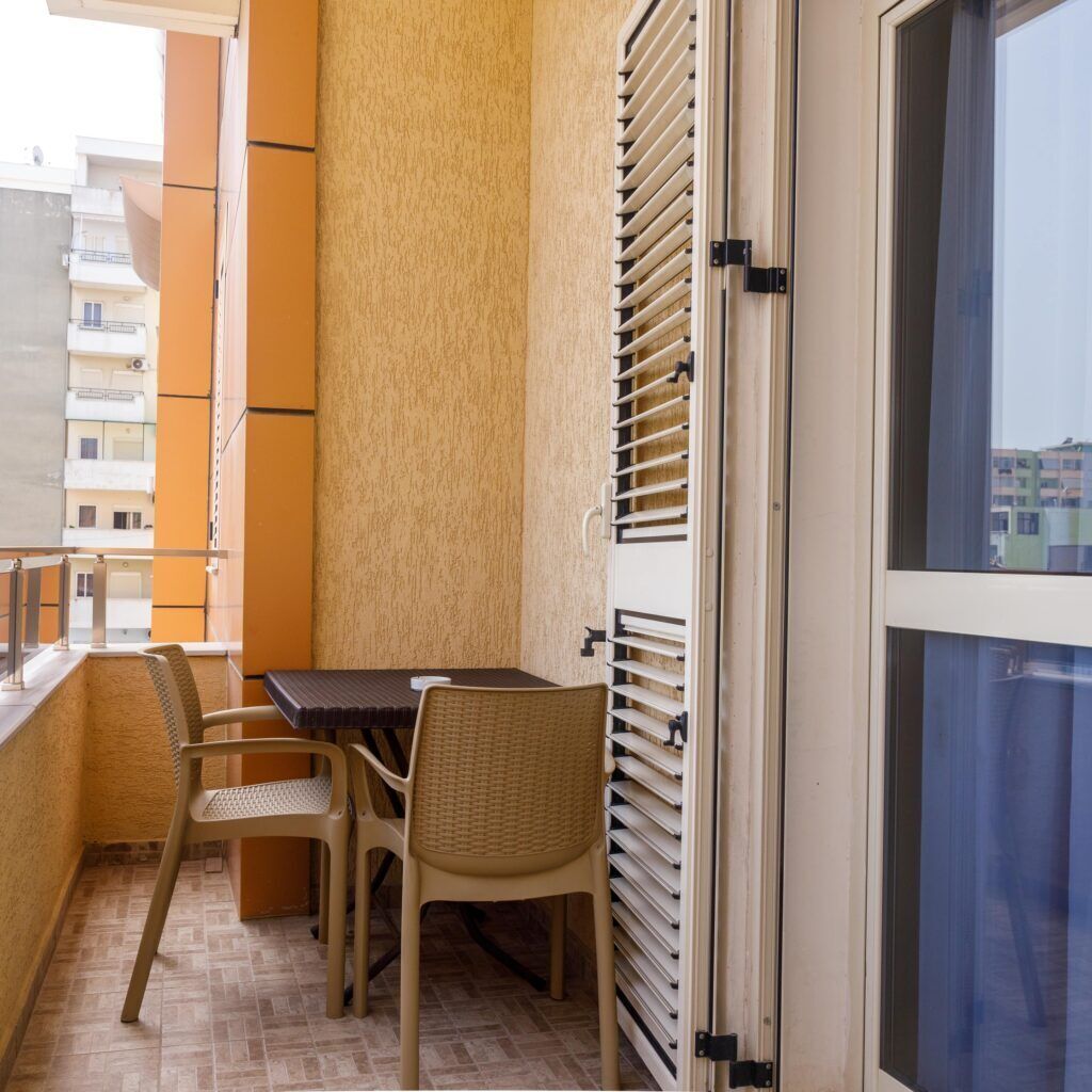 Varanda com mesa e cadeiras, porta de correr e vista para a paisagem urbana.