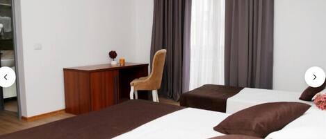 A hotel room with two beds, a desk, and a chair.
