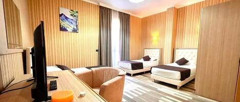 Ein Hotelzimmer mit zwei Betten, einem Schreibtisch, einem Fernseher, einer Fernbedienung und einem dekorativen Gegenstand auf dem Schreibtisch.