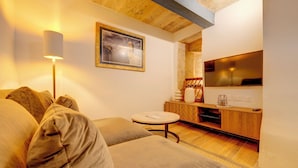 Un salon confortable avec un canapé, une petite table ronde, un téléviseur et un meuble en bois.