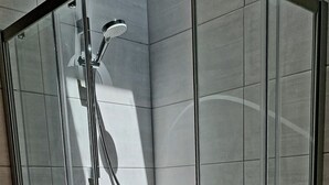 Cabina doccia in vetro con soffione a mano e miscelatore a parete.