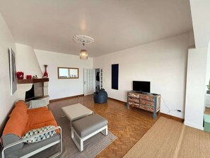 A spacious living room with a sofa, ottoman, and a TV stand. - Spacious 120 m² Seafront Apartment (Valras-Plage)