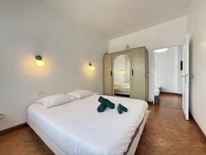 A hotel room with a large bed, two bedside lamps, a wardrobe, and a mirror. - Spacious 120 m² Seafront Apartment (Valras-Plage)