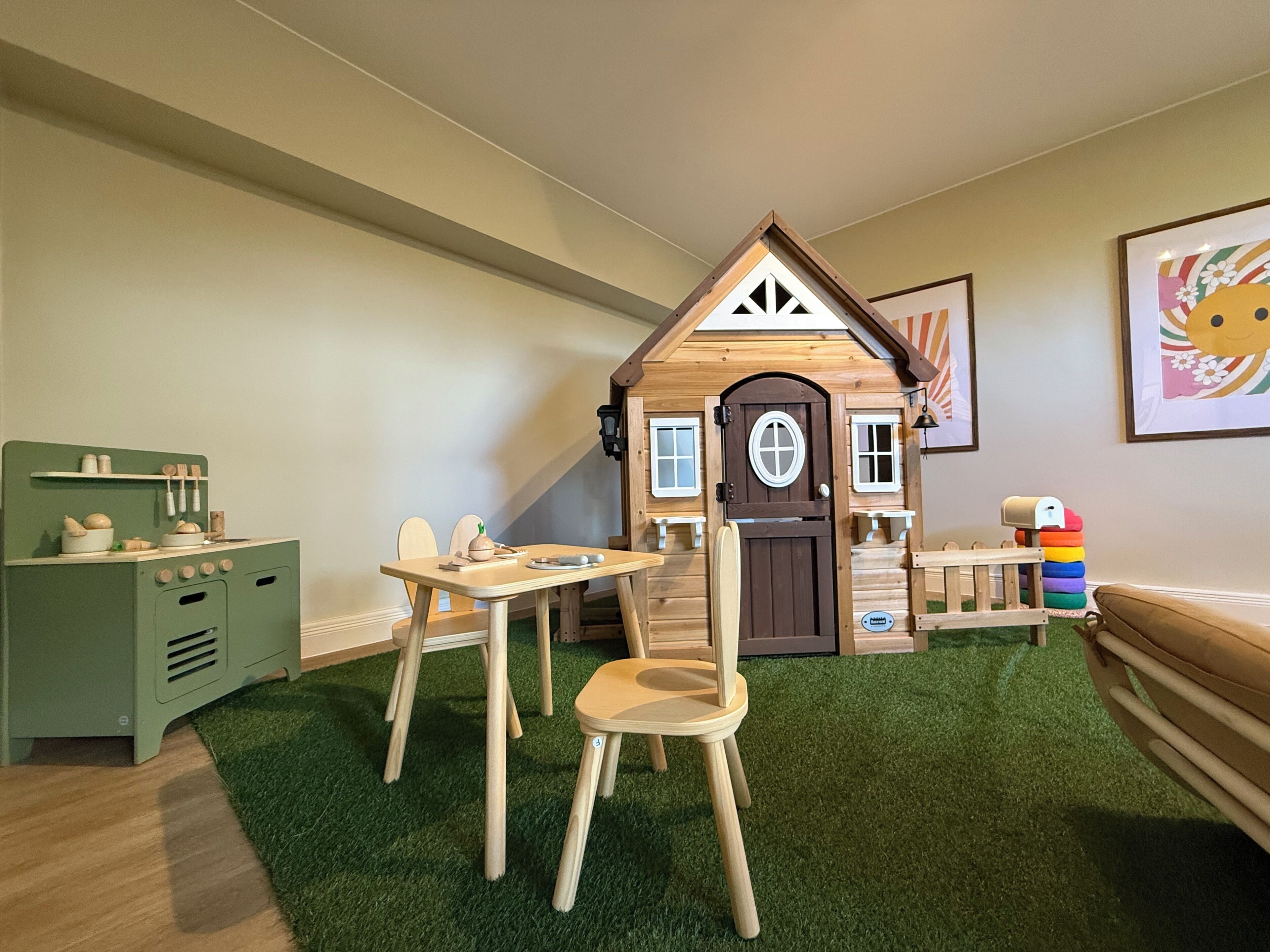 A playhouse with a door, windows, and a small table with chairs.