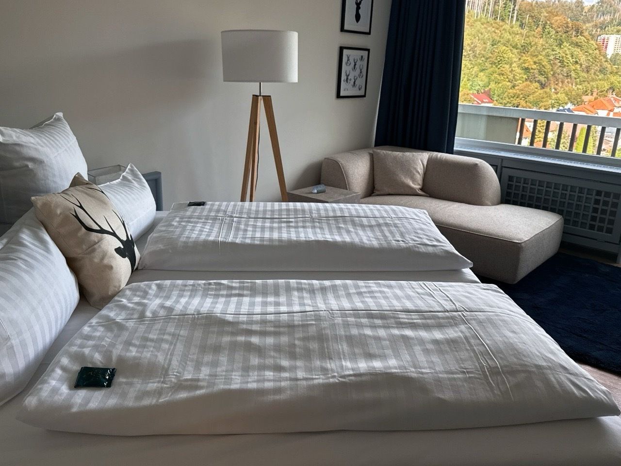 A hotel room with two beds, a sofa, a lamp, and a view of the outdoors.