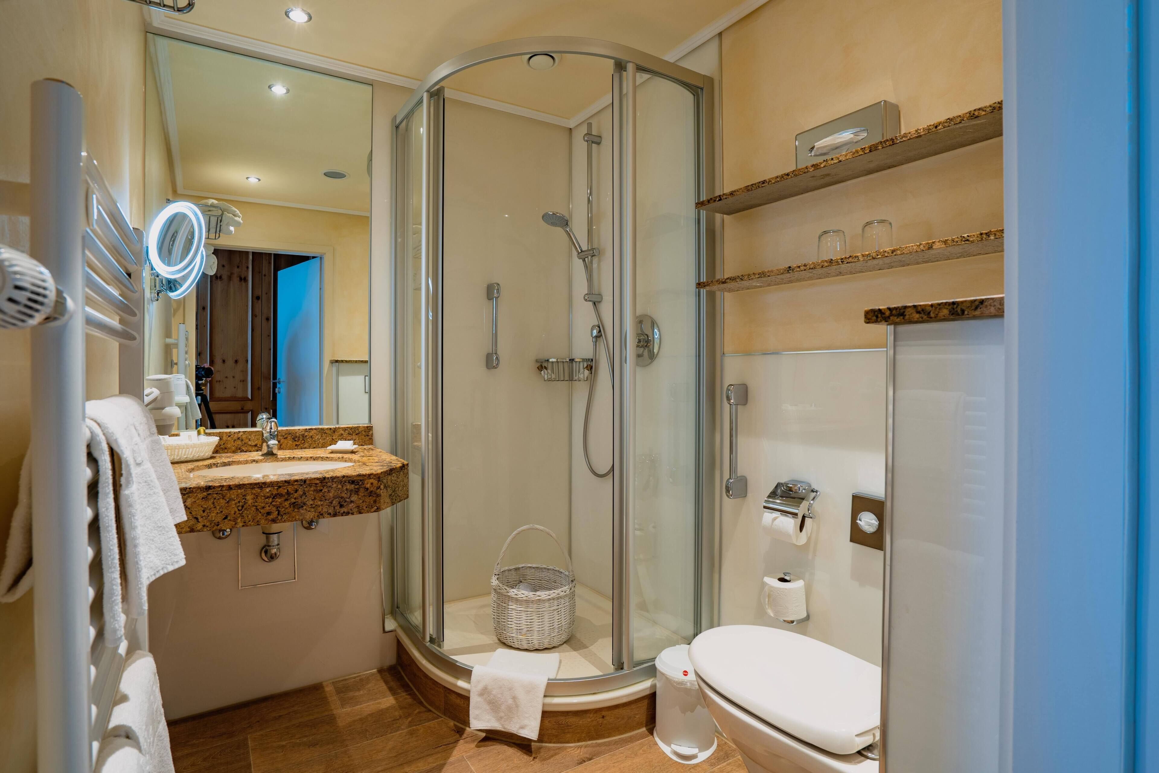 A modern bathroom with a glass-enclosed shower, a sink with a mirror, and a toilet.