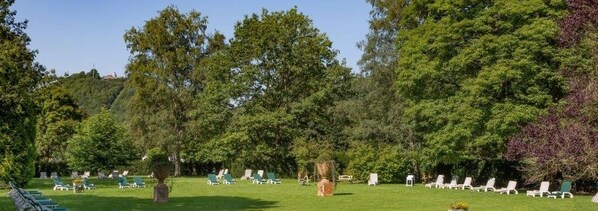 A grassy outdoor area with rows of white lounge chairs and a few trees. - re.vita - naturresort & spa (Bad Lauterberg)