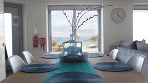 Un coin repas avec une table dressée pour six personnes, une vue sur la mer et un aménagement intérieur moderne.