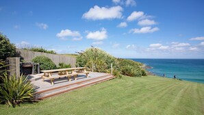 Un jardin avec une table de pique-nique en bois et un barbecue.