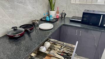 A kitchen with a marble backsplash, a microwave, a toaster, and a drawer organizer with utensils.