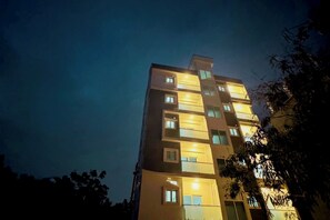 Ein mehrstöckiges Gebäude mit beleuchteten Fenstern und Balkonen bei Nacht.