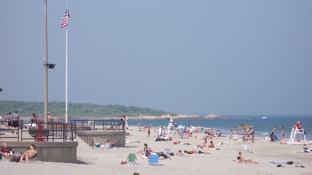 A beach with people sunbathing, a lifeguard tower, and a flagpole with an American flag. - Charming 1-bedroom cottage in beautiful Narragansett with AC, WiFi (Narragansett)