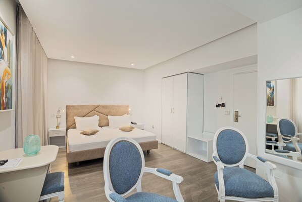 Una habitación de hotel moderna con una cama, dos sillas, un escritorio y un armario.