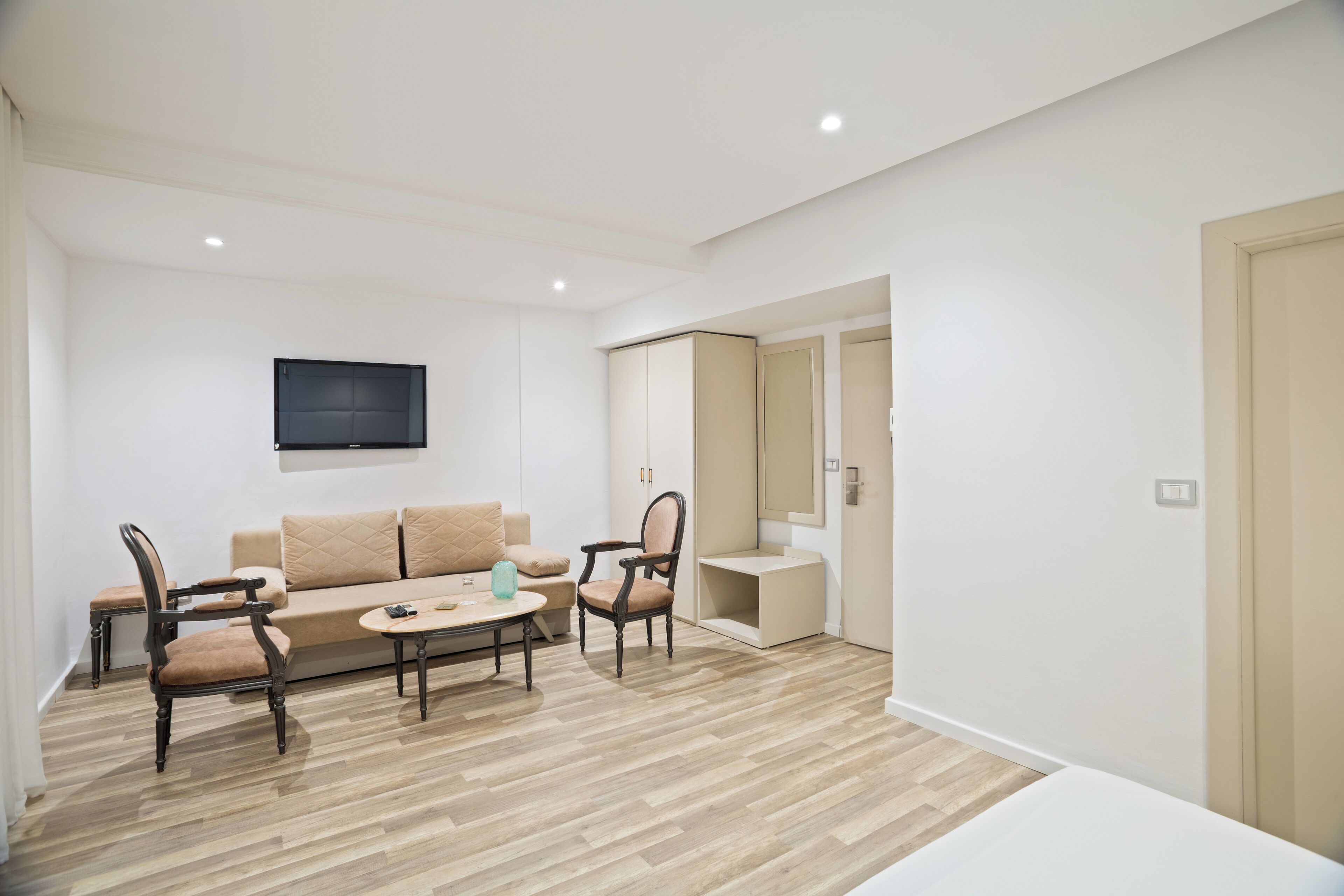 A modern living room with a sofa, two armchairs, a coffee table, and a flat-screen TV mounted on the wall.