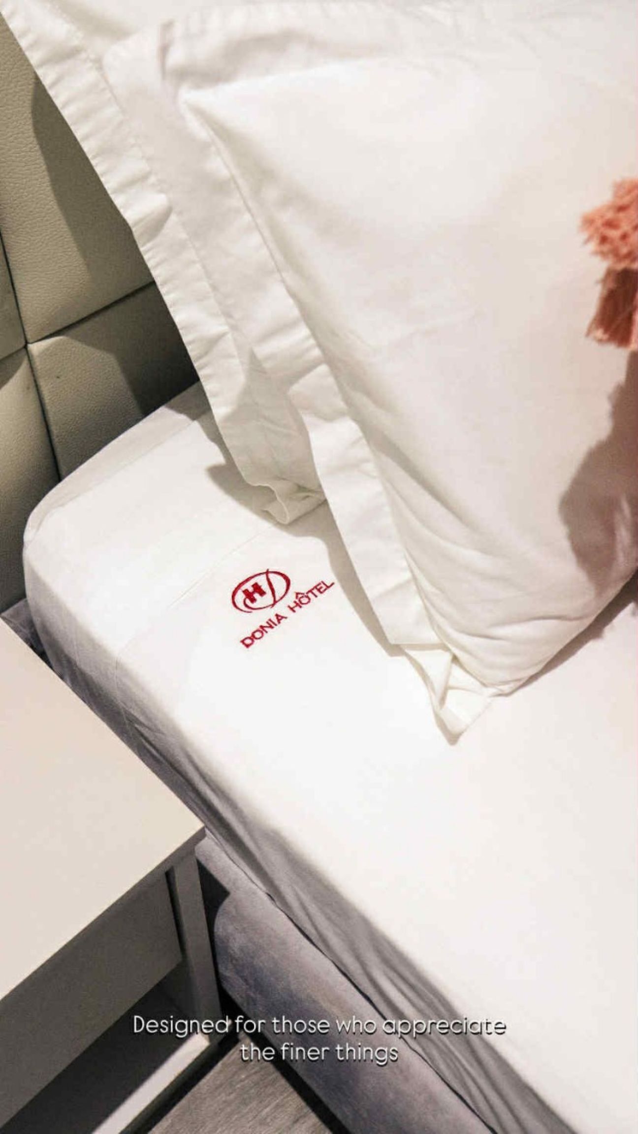 Una cama de hotel con un colchón blanco y una almohada con un logotipo.