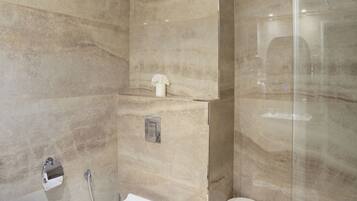 A modern bathroom with a freestanding bathtub, a toilet, and a glass-enclosed shower area.