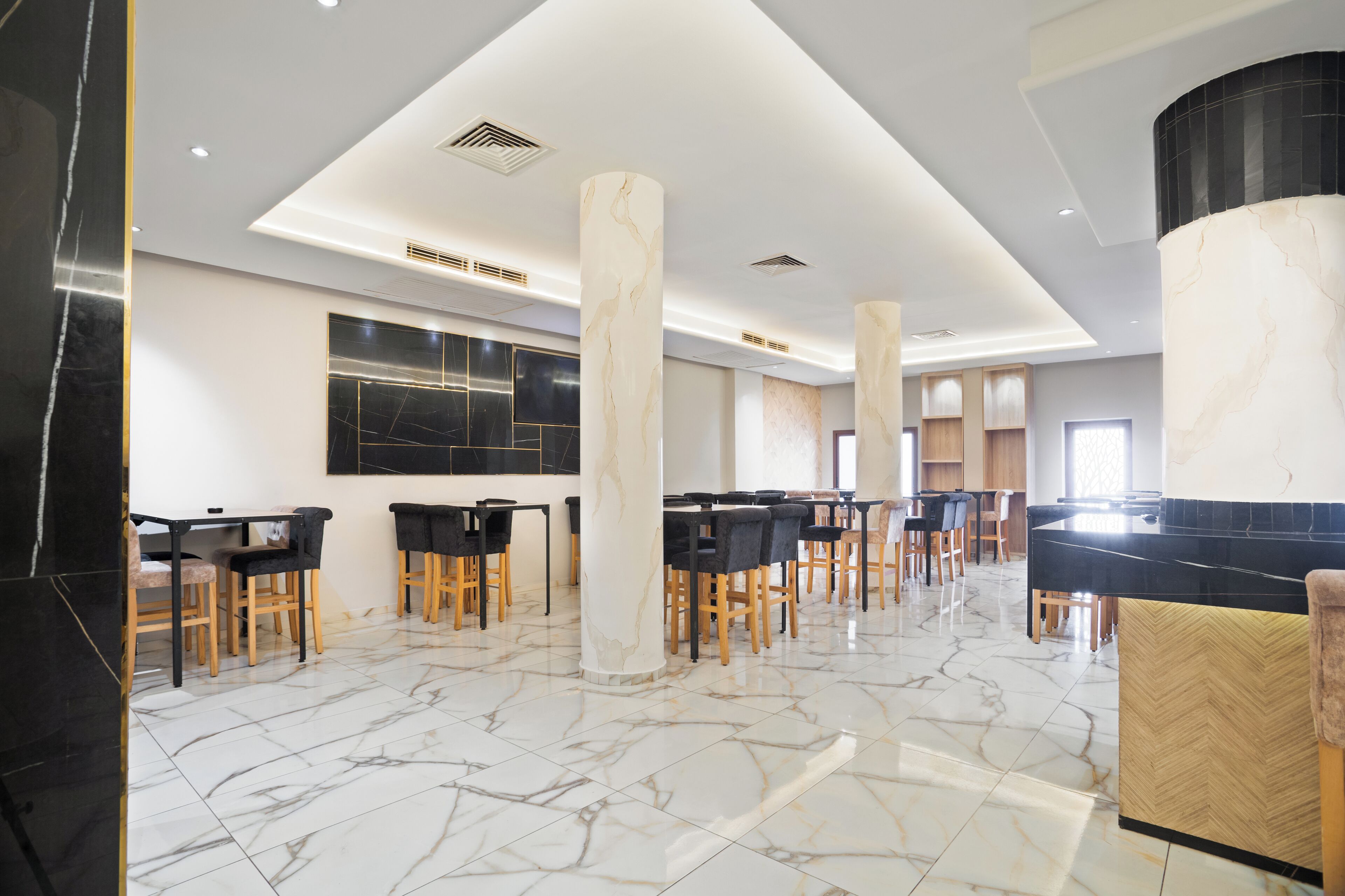 A spacious lobby with marble flooring, multiple seating areas, and a modern ceiling design.