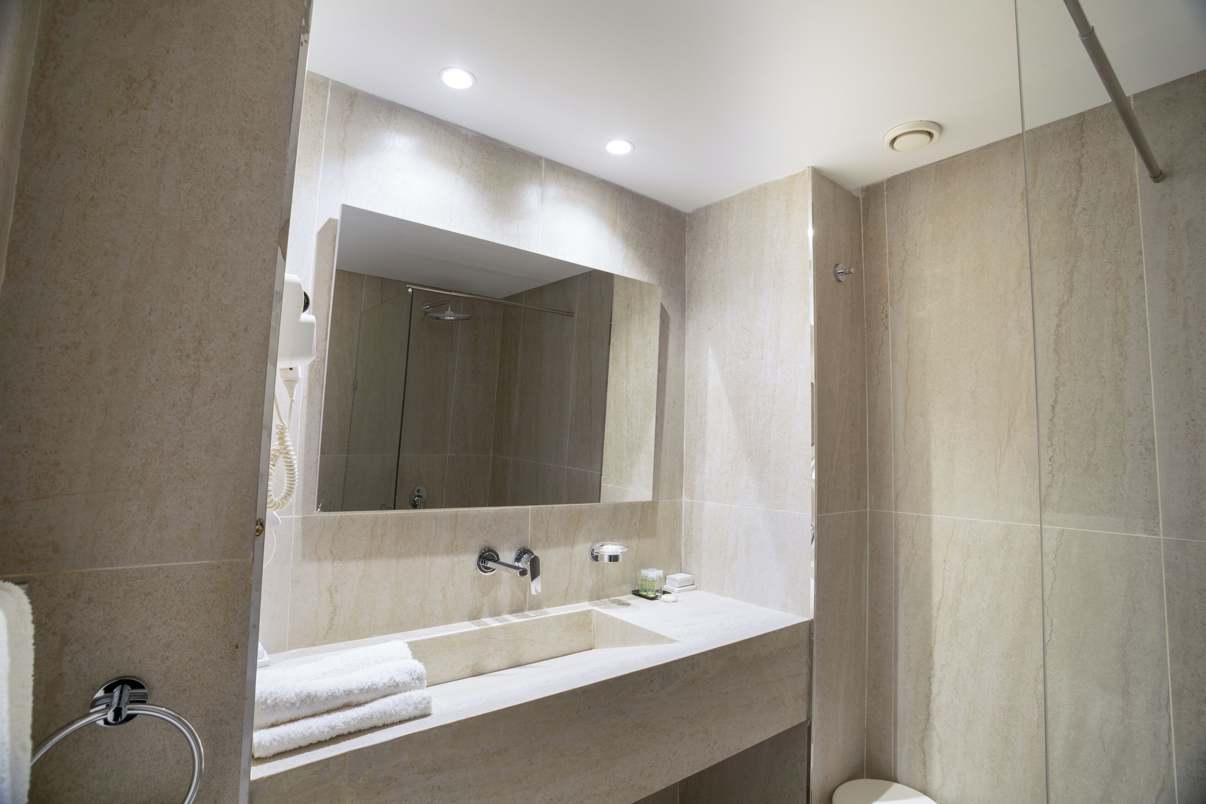 A modern bathroom with a large mirror, a sink, and a shower.