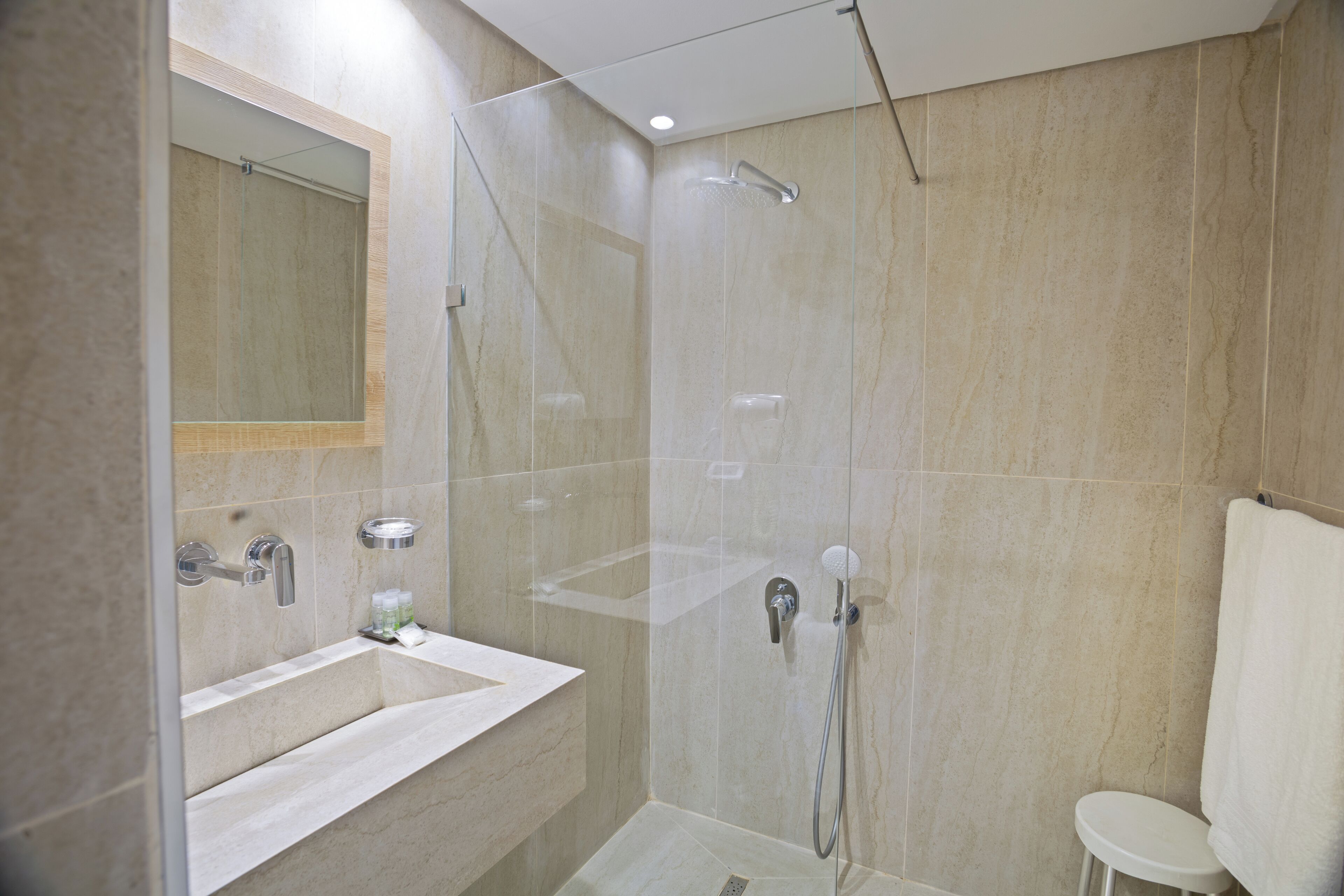 Un baño moderno con ducha de vidrio, un lavamanos con espejo y un inodoro.