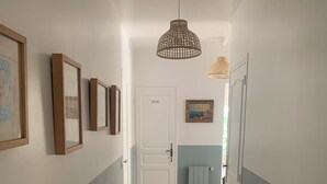 A hallway with wooden flooring, white walls, and a door at the end.