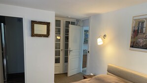 A bedroom with a bed, a wardrobe, a mirror, and a wall-mounted light fixture.