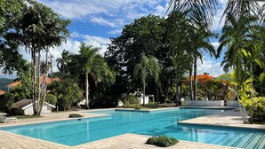 Ein rechteckiger Pool mit Fliesenrand, umgeben von einer gepflasterten Liegefläche.