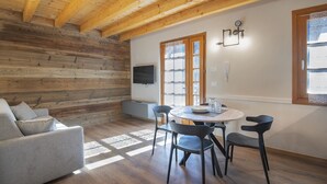 A cozy room with a wooden ceiling, a sofa, a dining table with chairs, and a TV mounted on the wall. - Silia's Home - Two Bedroom Apartment, Sleeps 4 (Vione)