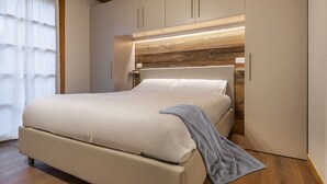 A modern bedroom with a bed, wooden panel wall, and built-in cabinets. - Silia's Home - Two Bedroom Apartment, Sleeps 4 (Vione)