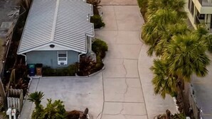Edificio residencial con garaje y entrada para vehículos, con vista a la playa.