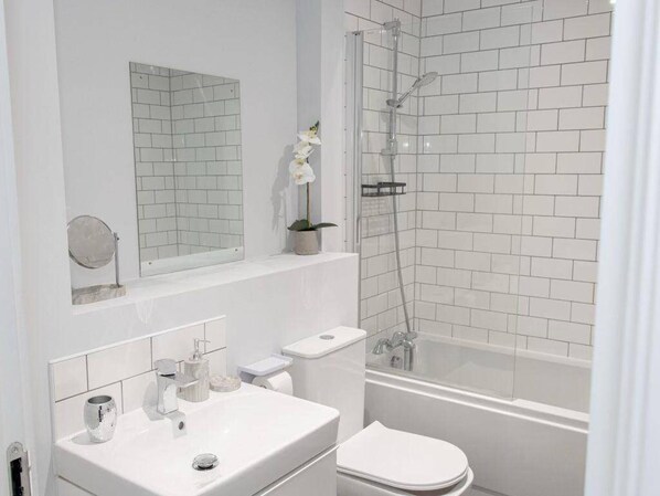 A modern bathroom with a white sink, toilet, and shower.