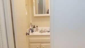 Une salle de bain avec un lavabo blanc, un miroir et des armoires.