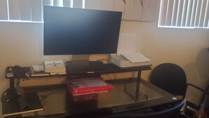Un bureau d’ordinateur avec un écran, un clavier et une souris. Il y a une boîte rouge sur le bureau.