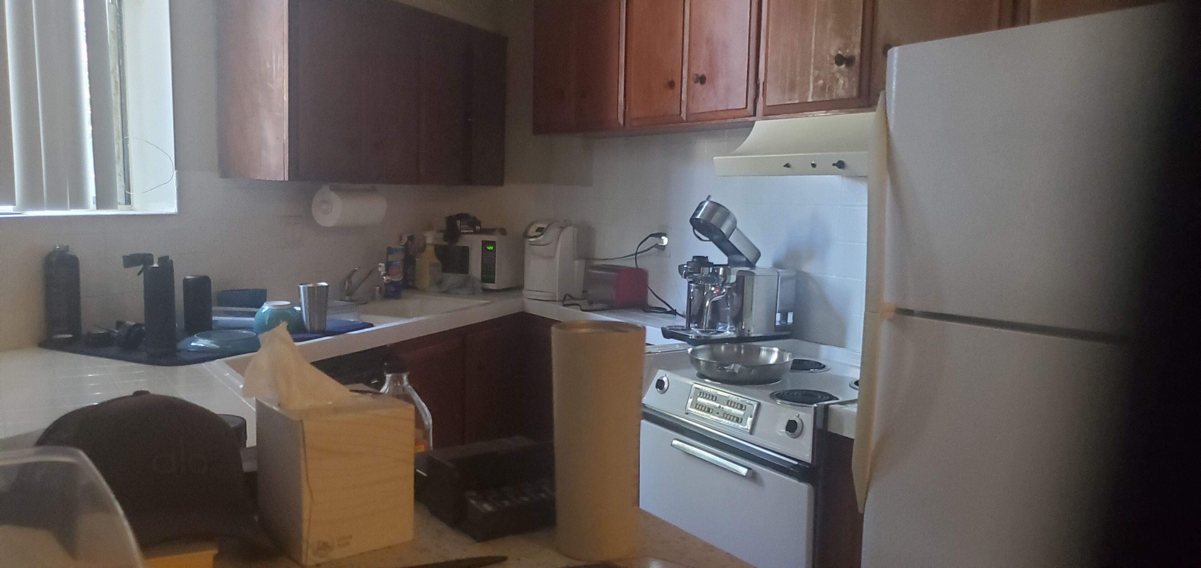 Een keuken met houten kastjes, een koelkast, een fornuis en diverse apparaten.
