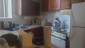Une cuisine dotée de meubles en bois, d’un réfrigérateur, d’une cuisinière et de divers appareils électroménagers.