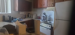 Una cucina con mobili in legno, un frigorifero, un piano cottura e diversi elettrodomestici.
