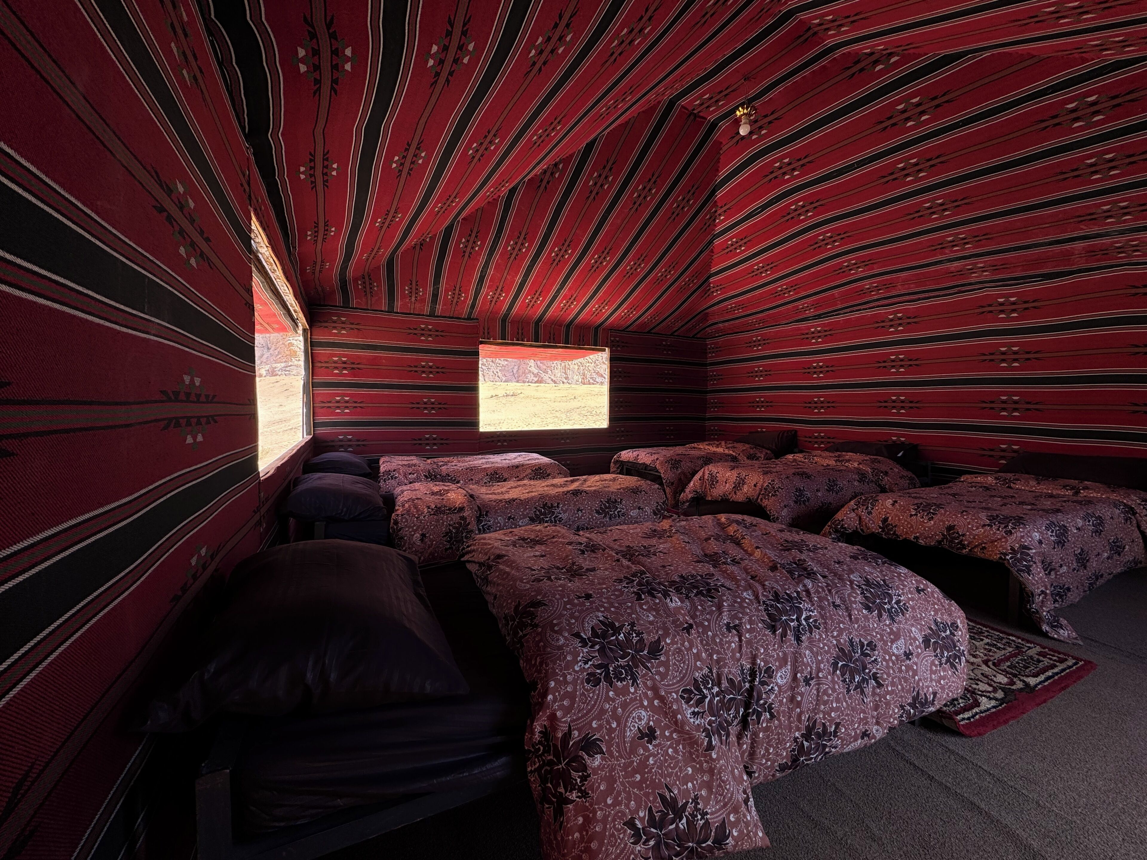 Una habitación con techo inclinado, paredes con diseño y una cama con colcha estampada.